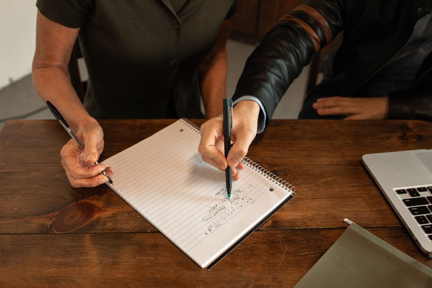 Hands putting ideas on paper beside an open laptop.